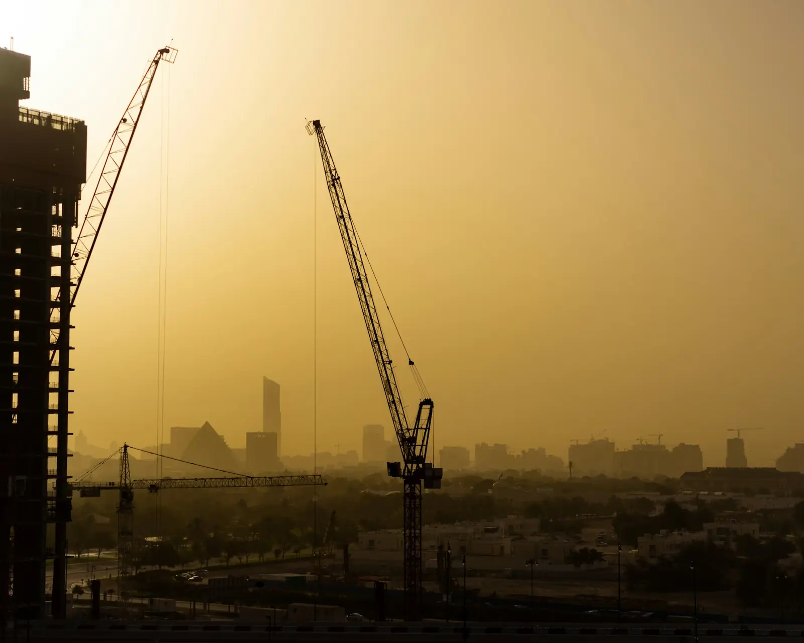 Construction cranes over Dubai at sunset